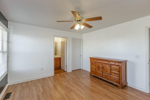 unfurnished bedroom featuring baseboards, visible vents, connected bathroom, ceiling fan, and light wood-style floors