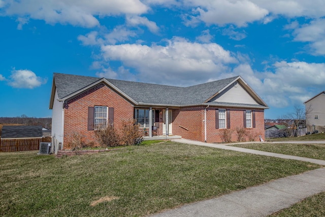 single story home featuring a shingled roof, a front yard, brick siding, and central air condition unit