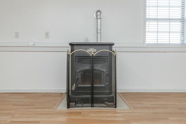 details featuring wood finished floors, a wood stove, and baseboards