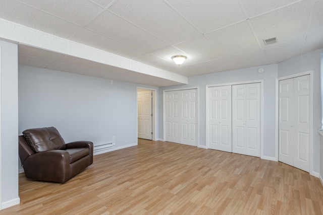 sitting room with light wood-style floors, baseboards, and a drop ceiling