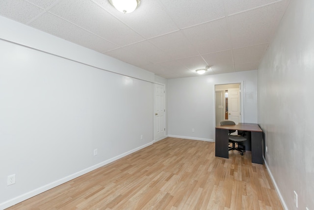 unfurnished office with a paneled ceiling, baseboards, and light wood finished floors