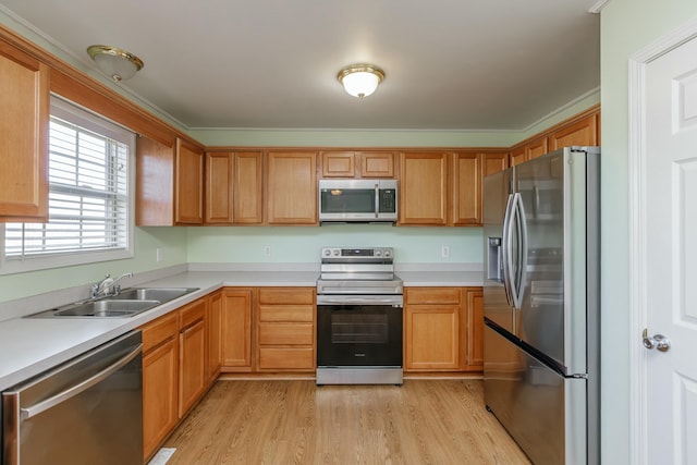 kitchen featuring appliances with stainless steel finishes, light countertops, a sink, and light wood finished floors