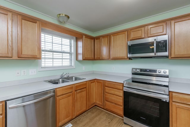 kitchen with light wood-style floors, stainless steel appliances, a sink, and light countertops