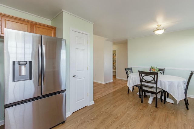 kitchen featuring brown cabinetry, stainless steel fridge, light wood-style flooring, and baseboards