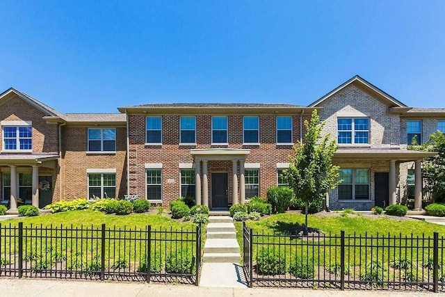 view of front of house with a front yard, brick siding, and a fenced front yard