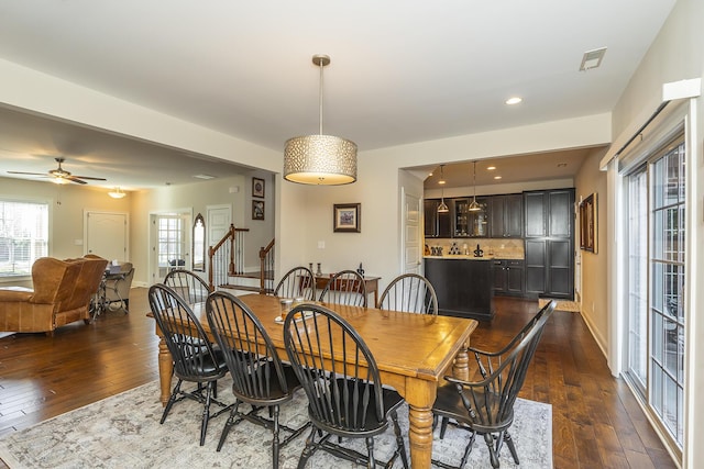 dining space featuring stairway, a healthy amount of sunlight, and dark wood-type flooring