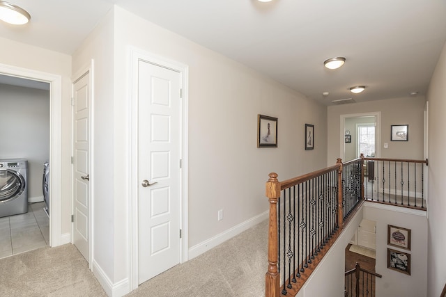 corridor with visible vents, baseboards, washer and clothes dryer, an upstairs landing, and light carpet