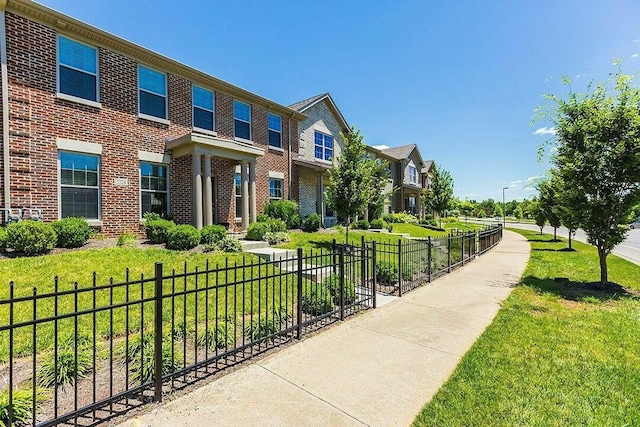 view of front of home with a front lawn, fence, and brick siding