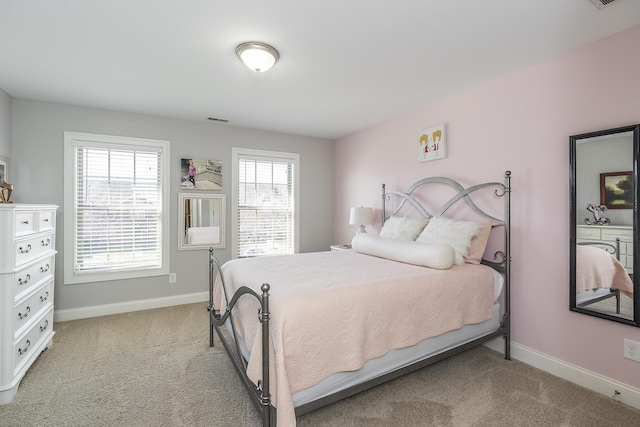 bedroom featuring visible vents, light colored carpet, and baseboards