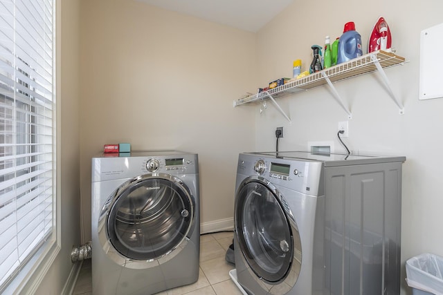 laundry room featuring laundry area, light tile patterned floors, washing machine and dryer, and baseboards