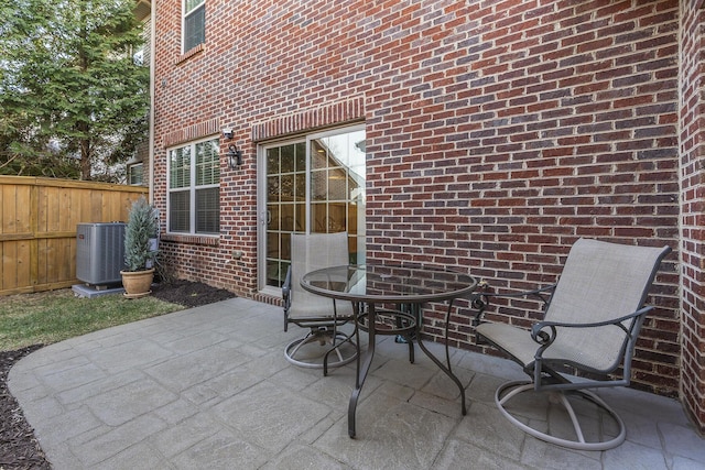 view of patio with outdoor dining area, central AC, and fence