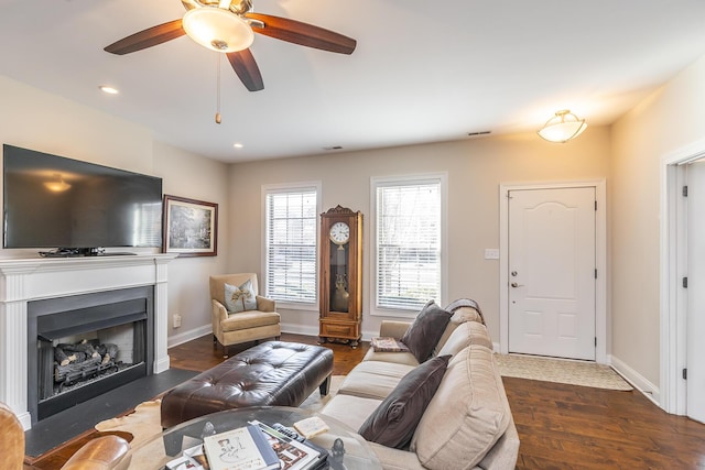 living room featuring visible vents, baseboards, a fireplace with flush hearth, recessed lighting, and wood finished floors