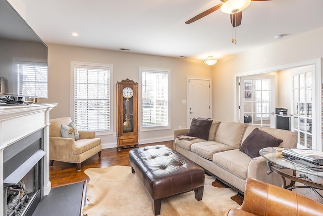 living room with wood finished floors, a fireplace with flush hearth, a healthy amount of sunlight, and visible vents