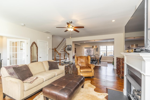 living room with a fireplace with flush hearth, wood finished floors, recessed lighting, baseboards, and stairs