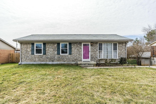 ranch-style house featuring stone siding, fence, a front lawn, and roof with shingles