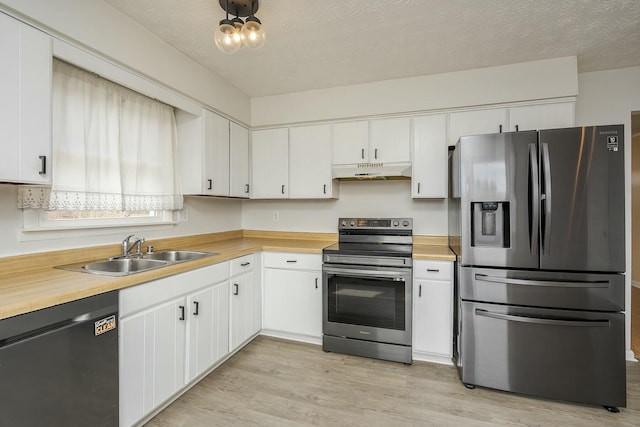 kitchen with a textured ceiling, under cabinet range hood, stainless steel appliances, a sink, and light wood-type flooring