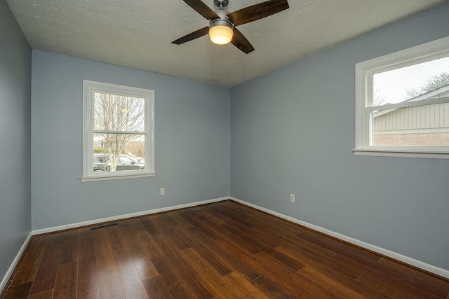 empty room featuring a textured ceiling, ceiling fan, hardwood / wood-style flooring, visible vents, and baseboards