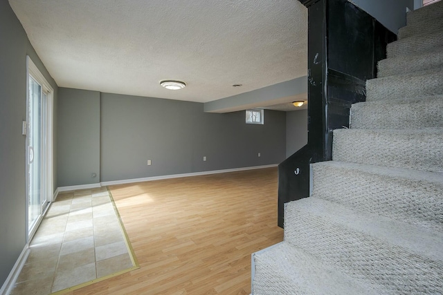 stairs featuring a textured ceiling, baseboards, and wood finished floors