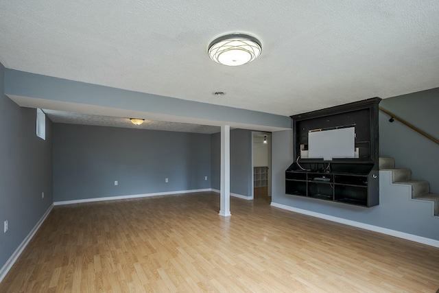 unfurnished living room featuring stairway, a textured ceiling, and wood finished floors