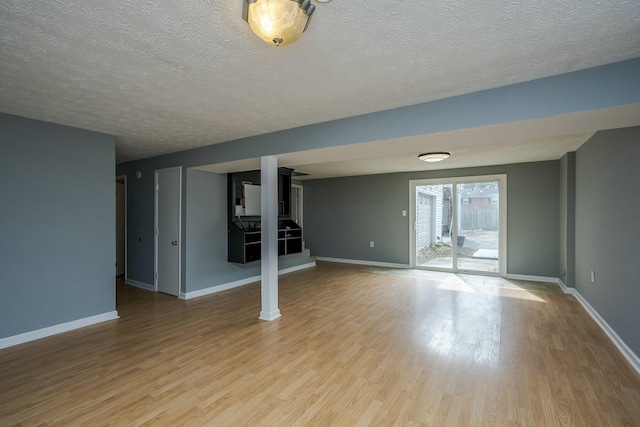 basement with a textured ceiling, wood finished floors, and baseboards