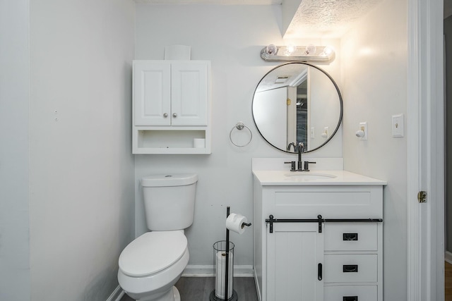 half bathroom featuring vanity, toilet, and baseboards