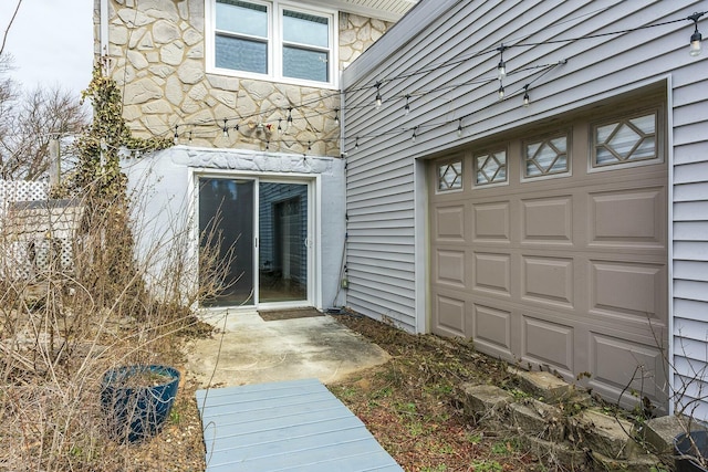 doorway to property with a garage and stone siding