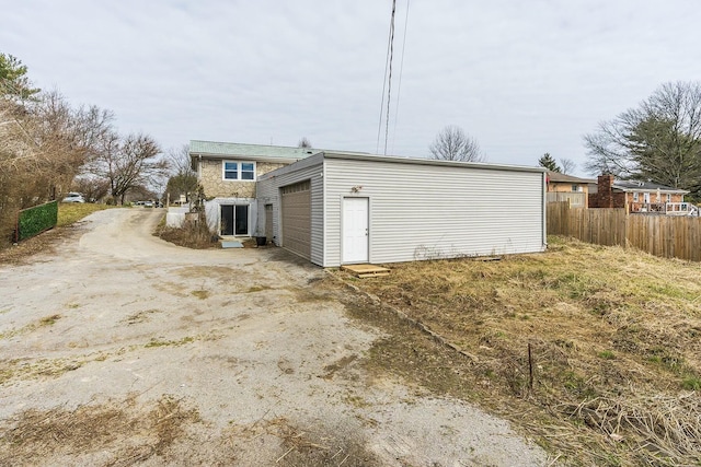 exterior space featuring a garage, an outbuilding, fence, and driveway