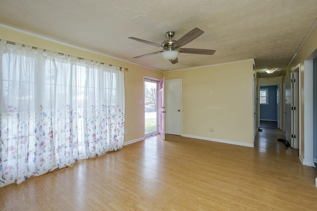 spare room featuring baseboards, light wood-style flooring, and a textured ceiling