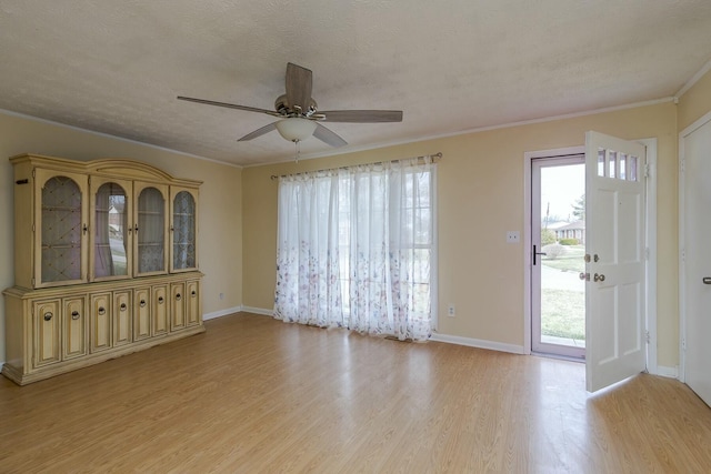 spare room with light wood-style floors, a healthy amount of sunlight, crown molding, and a textured ceiling