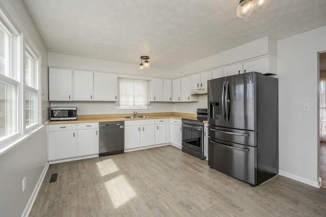 kitchen with wooden counters, appliances with stainless steel finishes, and light wood-style floors