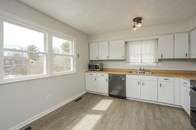 kitchen with a sink, white cabinets, baseboards, appliances with stainless steel finishes, and light wood-type flooring