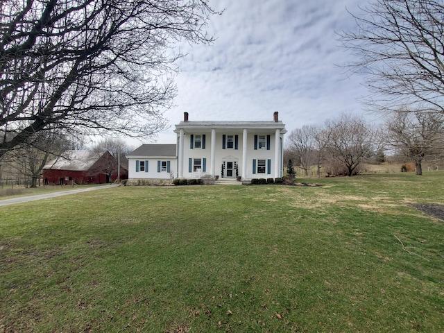 greek revival house featuring a chimney and a front lawn