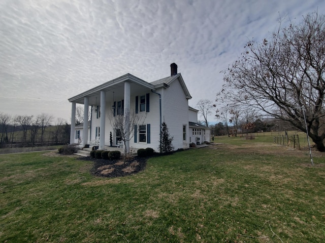 view of property exterior with a porch, a lawn, and a chimney