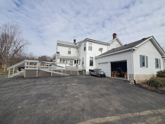 back of house featuring an attached garage, aphalt driveway, and a wooden deck