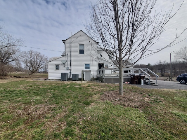 rear view of property featuring central AC, a lawn, and a deck