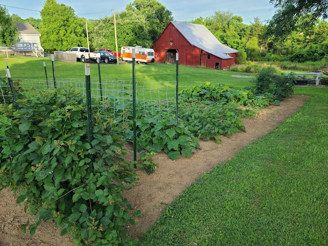 view of yard featuring a garden, an outdoor structure, a barn, and fence