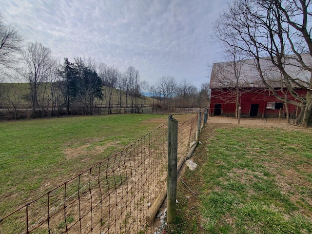 view of yard with a rural view, an outdoor structure, a barn, and fence