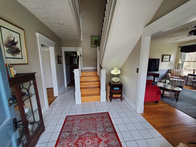 interior space featuring a textured ceiling, stairway, tile patterned flooring, and a ceiling fan