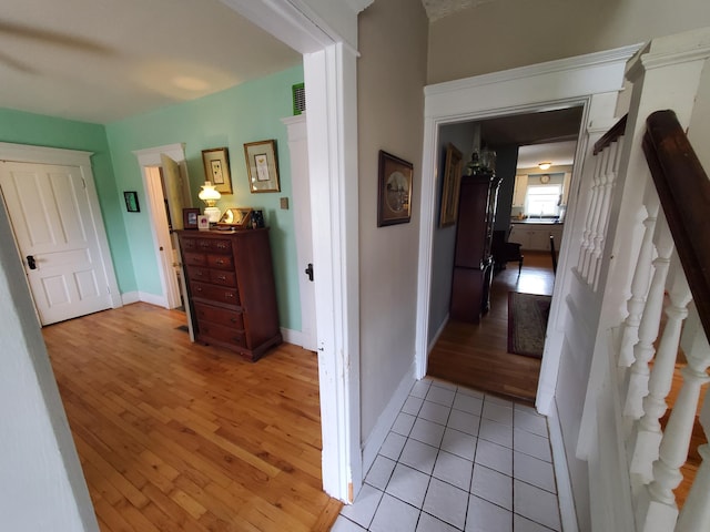 hall with light wood-type flooring, stairs, and baseboards