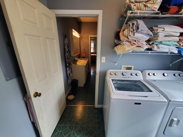 laundry area featuring laundry area, baseboards, washer and clothes dryer, and dark tile patterned flooring