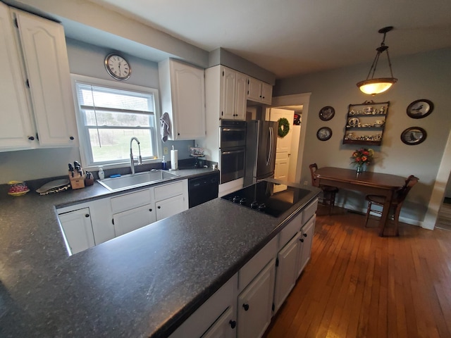 kitchen with dark wood-style flooring, dark countertops, white cabinets, a sink, and black appliances