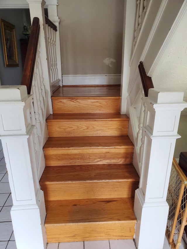 staircase with ornate columns and baseboards