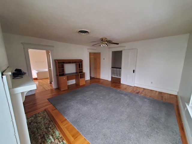 unfurnished living room with a ceiling fan, visible vents, and wood finished floors