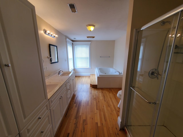 full bathroom featuring visible vents, a stall shower, a sink, wood finished floors, and a bath