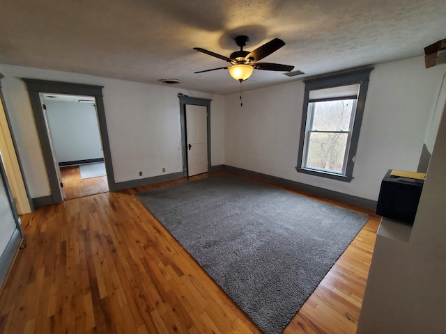 unfurnished bedroom featuring baseboards, a textured ceiling, visible vents, and wood finished floors