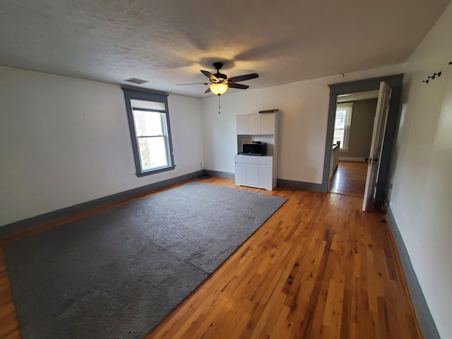 unfurnished living room featuring a ceiling fan, plenty of natural light, light wood-style flooring, and baseboards