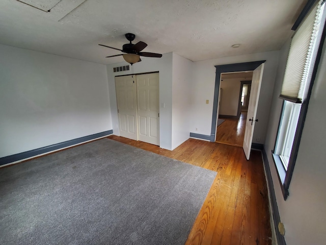 unfurnished bedroom featuring a closet, visible vents, ceiling fan, wood finished floors, and baseboards