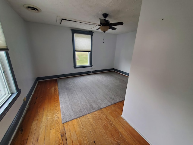 empty room featuring hardwood / wood-style flooring, baseboards, visible vents, and ceiling fan