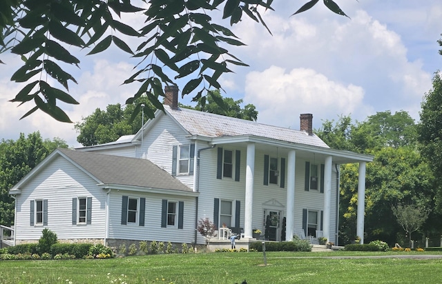 view of front of property featuring a chimney, a porch, and a front yard