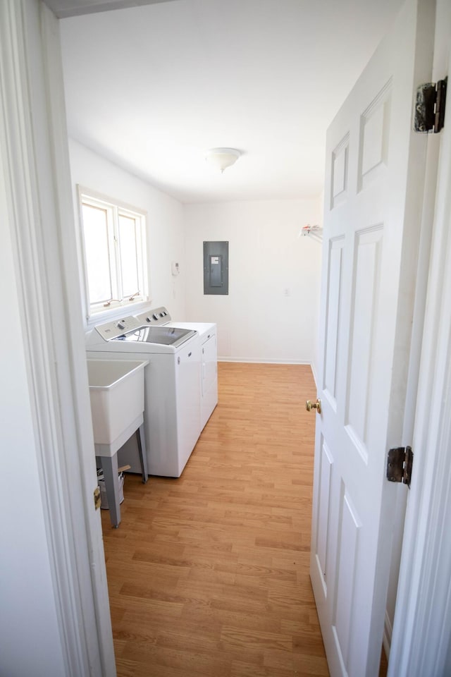 laundry room featuring laundry area, baseboards, light wood-style floors, independent washer and dryer, and electric panel